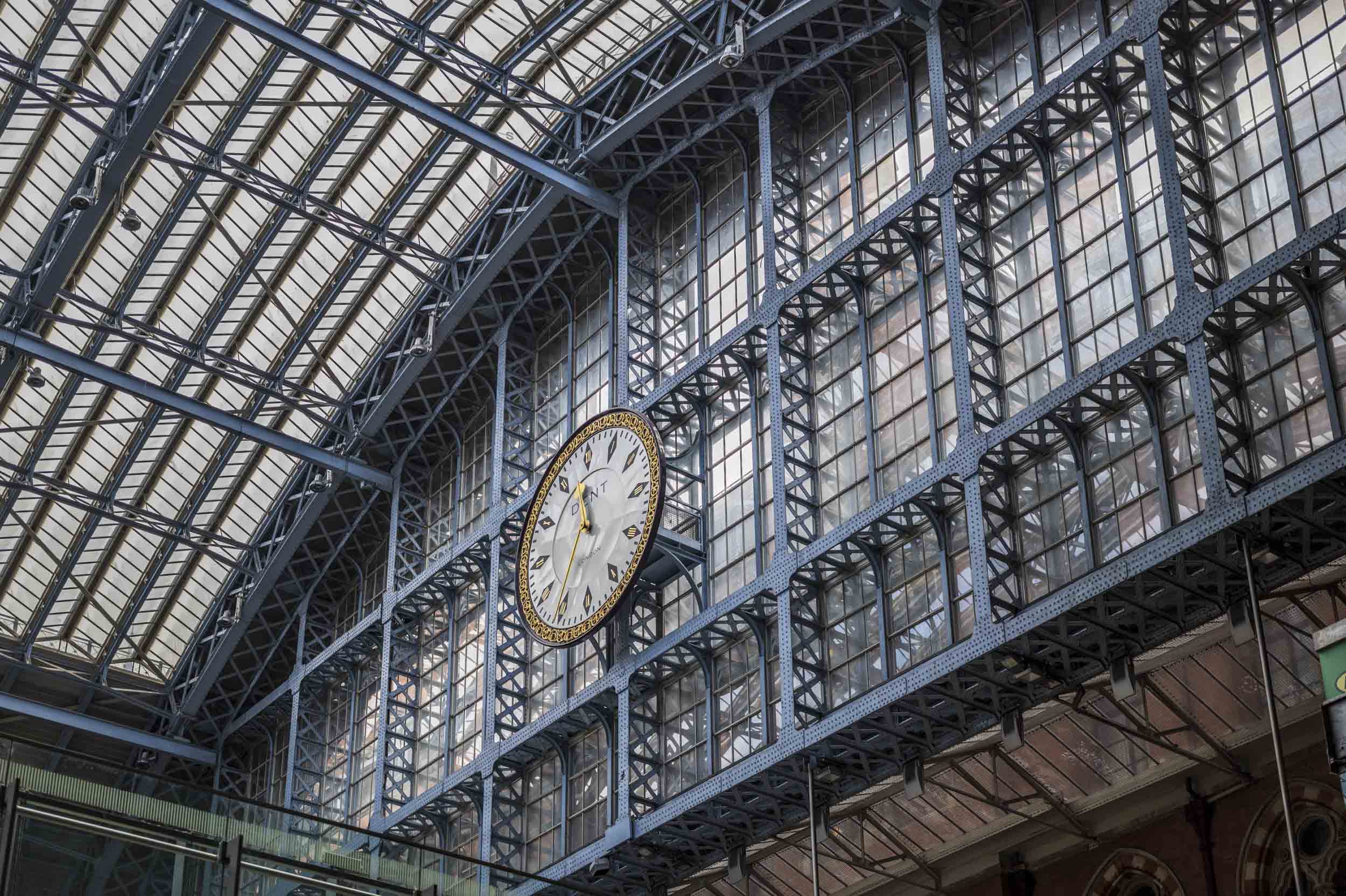 A Dent clock mounted beneath the glazed iron-framed roof of King's Cross railway station in London