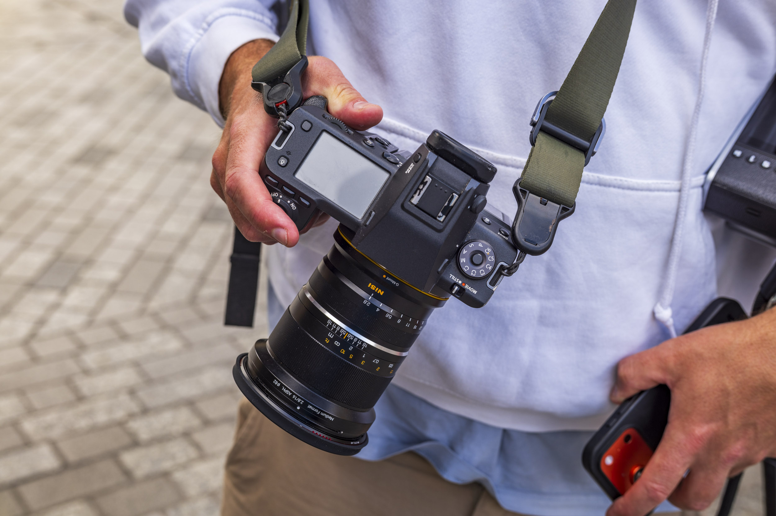 A close-up of a Fujifilm medium-format camera fitted with a NiSi 14mm f/2.8 lens, held in a photographer's hand.