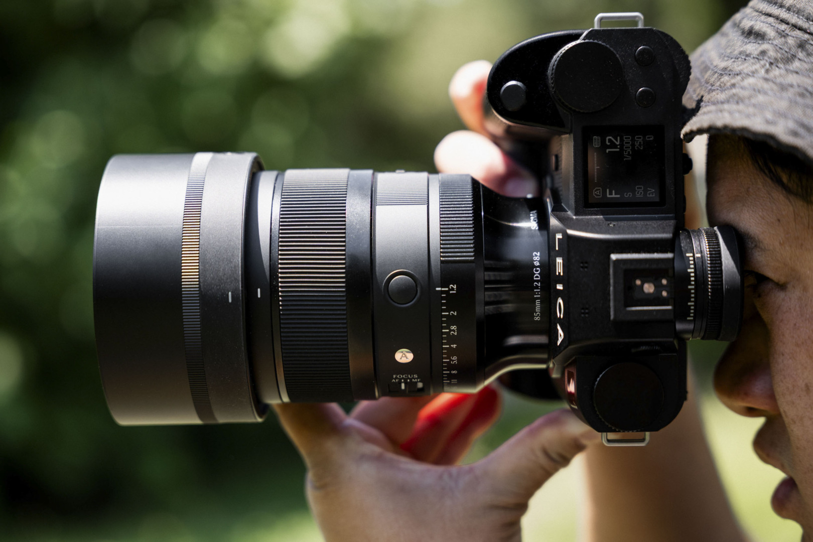 A close-up of a photographer's eye looking through the viewfinder of a Leica camera fitted with the 85mm f/1.2 lens.