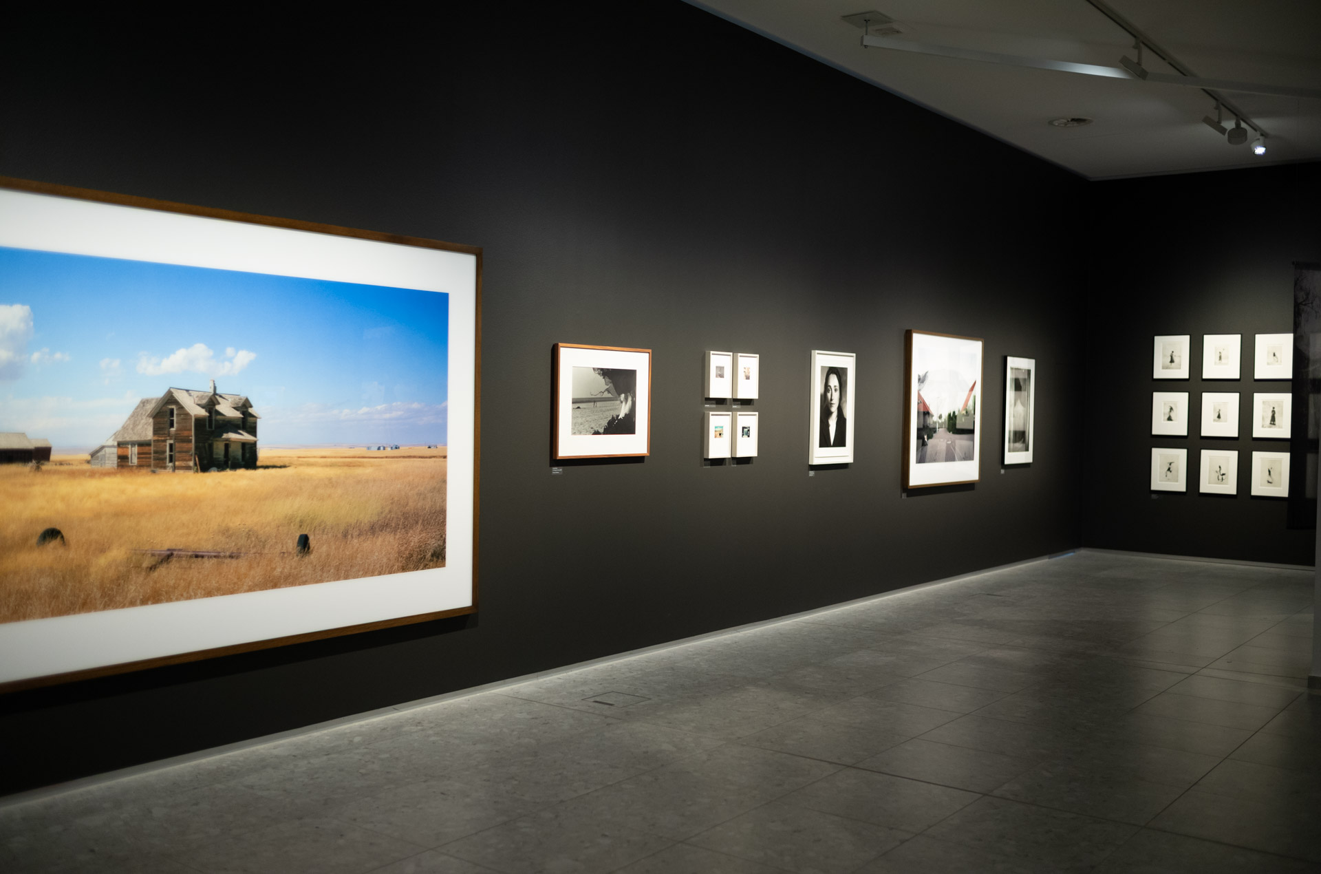 Leica Wetzlar visit: A gallery wall with a large colour photograph of an abandoned prairie farmhouse beside smaller black-and-white and colour prints.