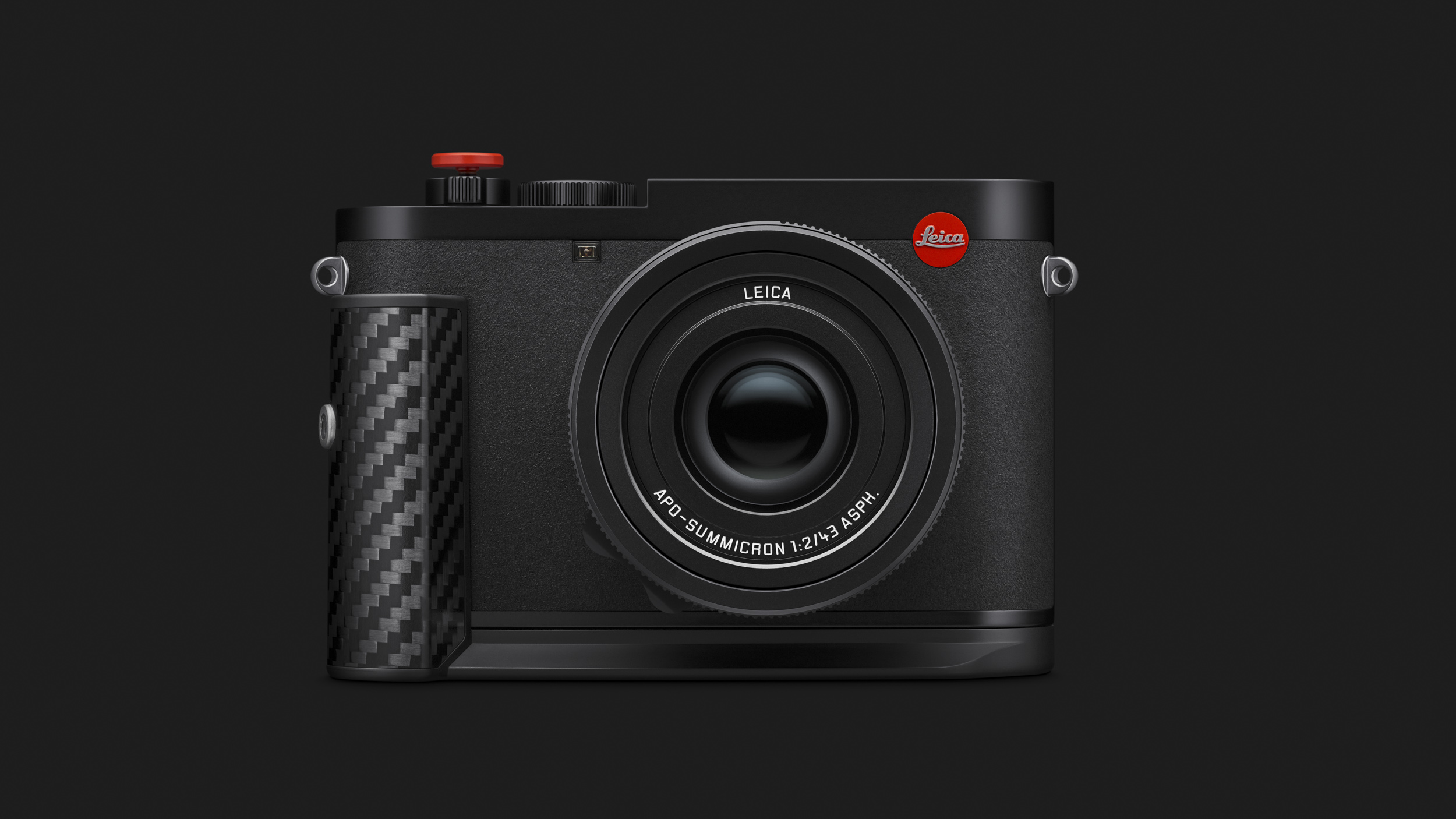 Straight-on front view of the camera with its carbon fibre handgrip and red Leica badge on a plain dark grey background.