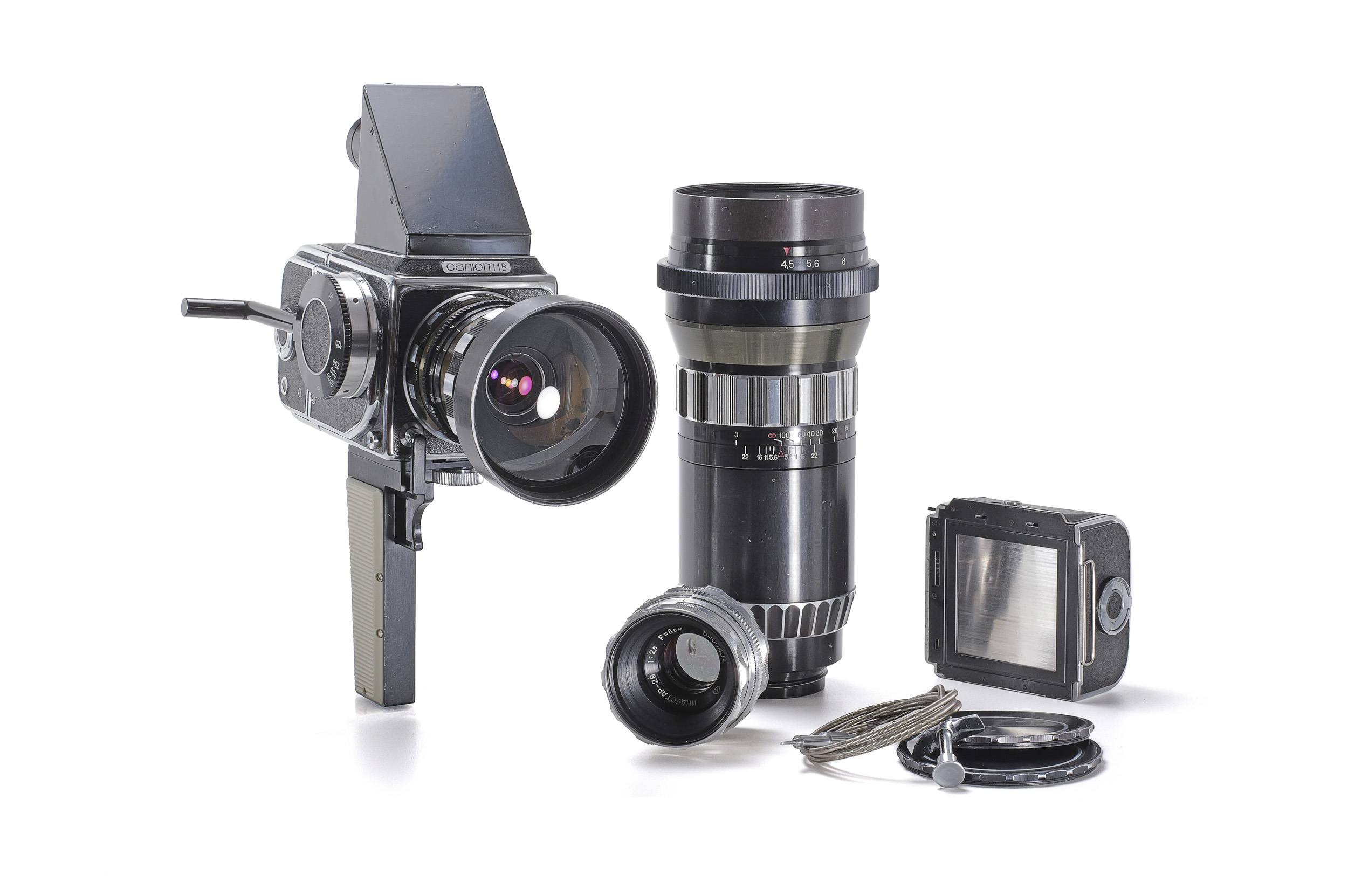 A Soviet Salyut medium-format camera with a pistol grip and prism finder, alongside a long telephoto lens, a standard lens and a film back.
